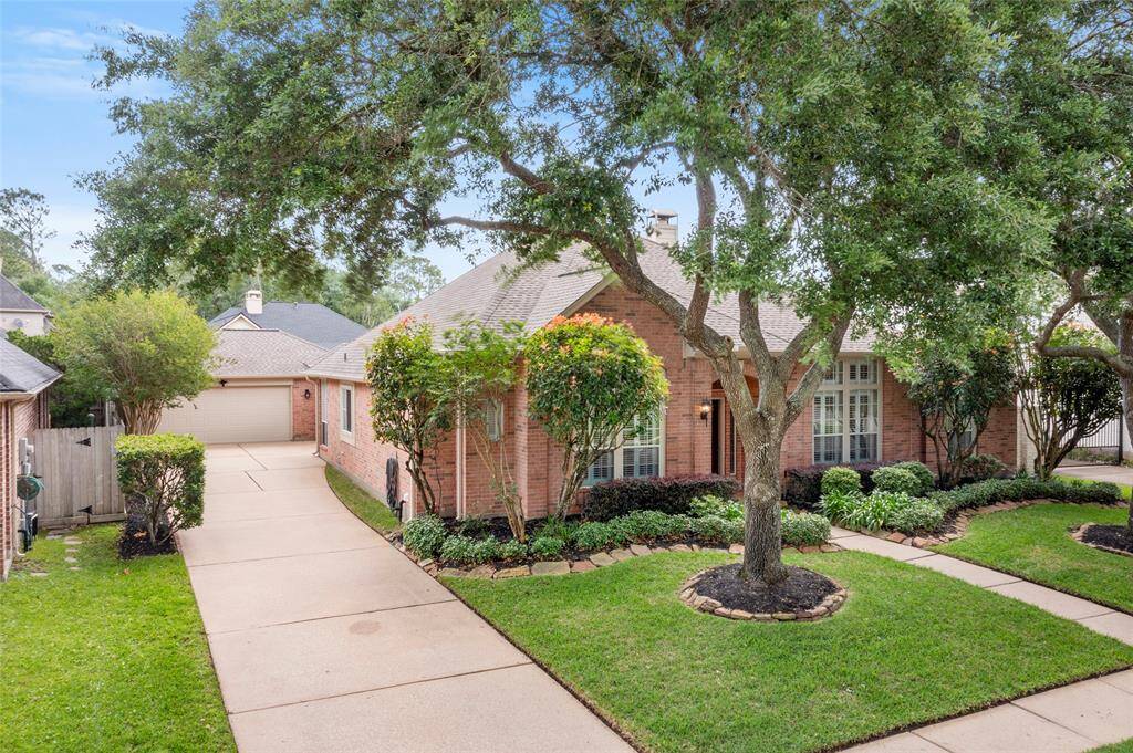 Charming brick home with a well-maintained front yard and mature trees that flank the front entry. Features a long driveway leading to a detached, oversized garage, and lush landscaping enhances curb appeal.