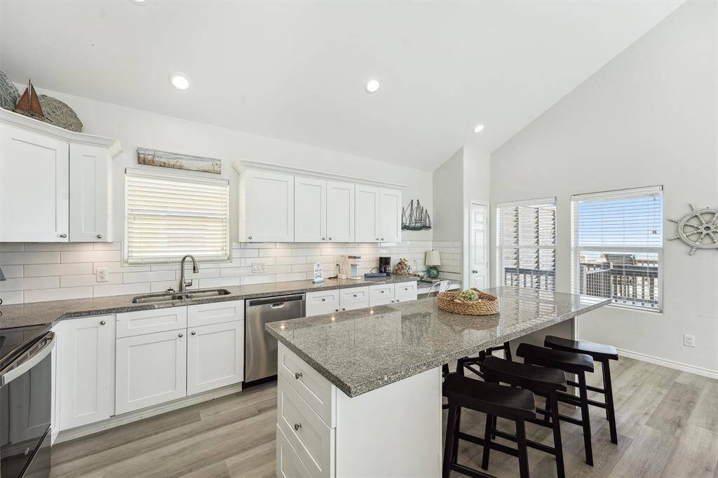 The chef-style kitchen offers ample counter space, crisp white cabinetry, and a large island with seating for casual meals or cocktails.