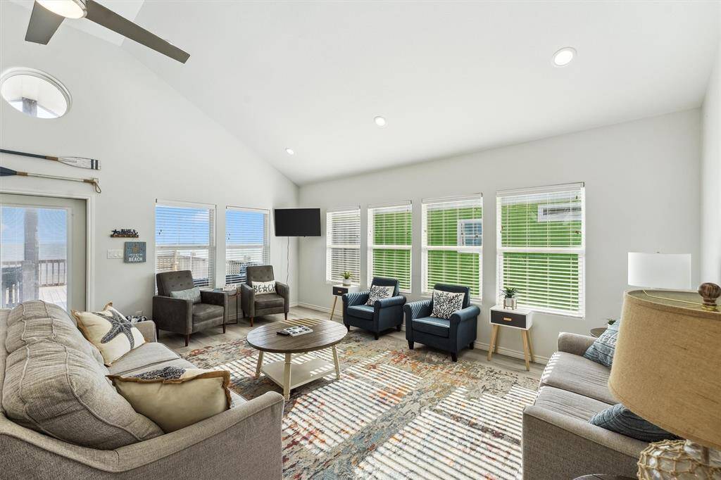 Light-filled and open, the main living area features soaring ceilings, coastal-inspired decor, and a chef's kitchen perfect for entertaining.
