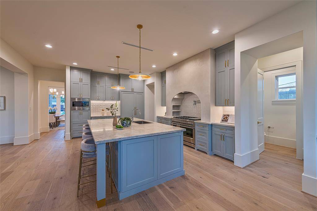 This chef's dream kitchen is centered around the custom island topped with Taj Mahal Quartzite, and hand plastered vent hood. The paneled appliances offer a sleek look along with the milky zellige backsplash.