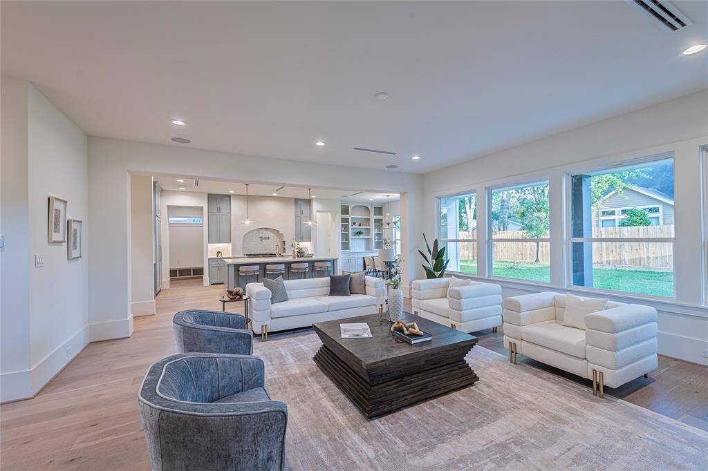 A seamless flow from living to kitchen to dining is perfect for modern living and sophisticated entertaining. Natural light pours in through oversized windows, highlighting a cozy fireplace.