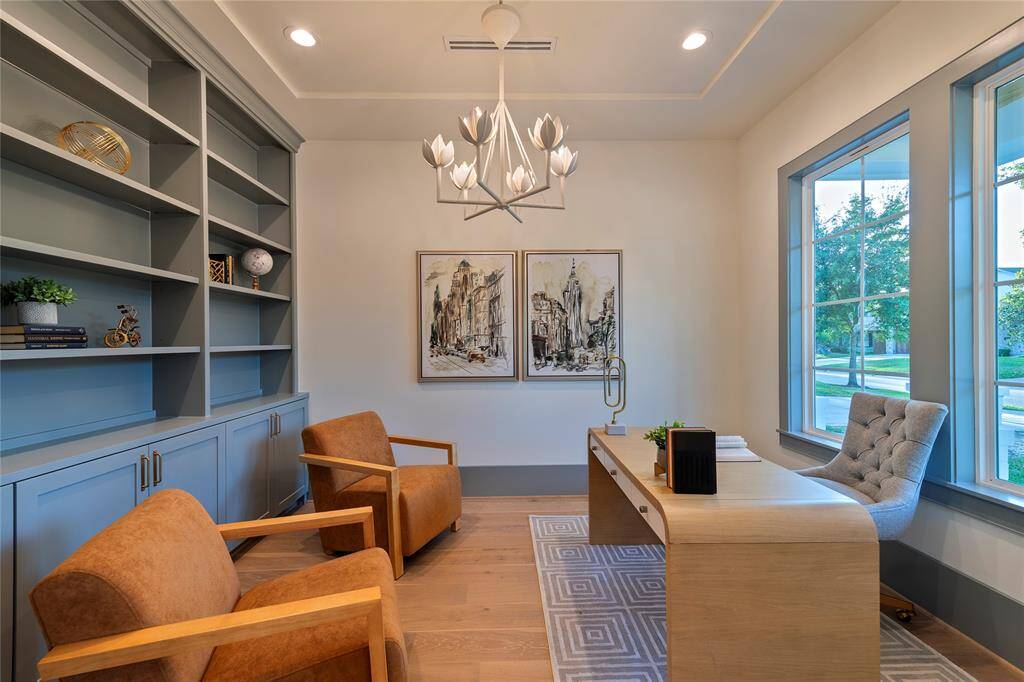 Handsome office just off of the entry is adorned with built in book shelves and visual comfort chandelier.