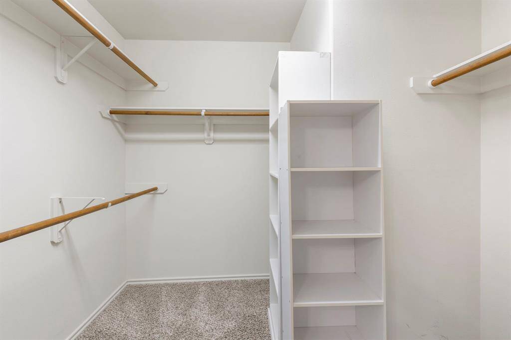 Generously sized walk-in primary closet with built-in storage, perfect for organizing purses, shoes, or other accessories.