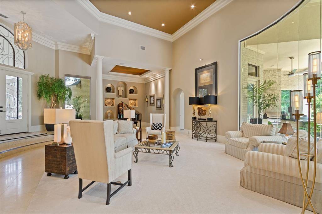 Another view of this spacious living area features high ceilings, elegant columns, and plenty of lighting. The open layout creates a welcoming and luxurious atmosphere ideal for entertaining or relaxing.