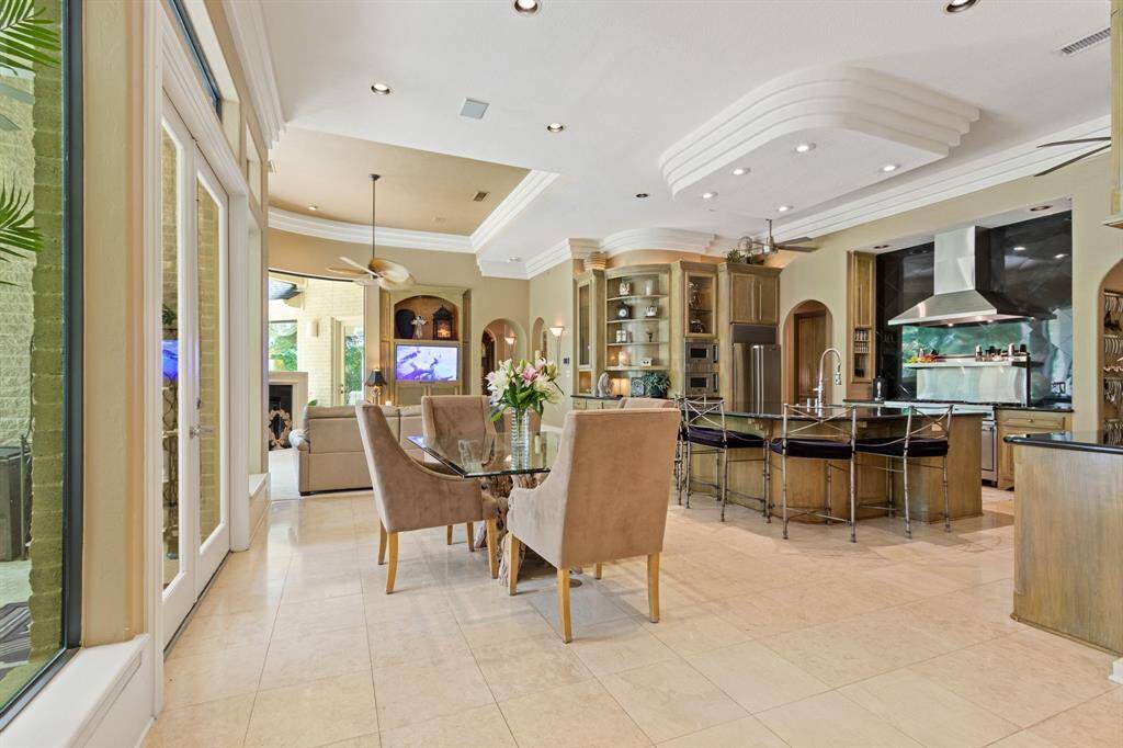 This photo showcases a spacious open-concept breakfast area with a modern kitchen, featuring a large island with bar seating, stainless steel appliances, and elegant cabinetry.  The family room offers a cozy sitting space with a view of the outdoors through large windows. The room is bright, airy, and perfect for entertaining.