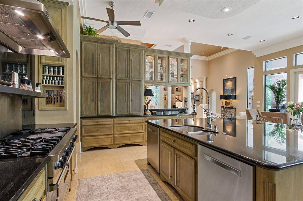 This spacious kitchen features elegant White oak cabinetry, a large island with granite countertops, and lighted cabinets to display your dishes.  Beyond the main kitchen, the home offers 4 additional food prep areas: the baker's room, main utility/office area, summer kitchen, & flex room of the garage., all thoughtfully designed for large scape entertaining.
