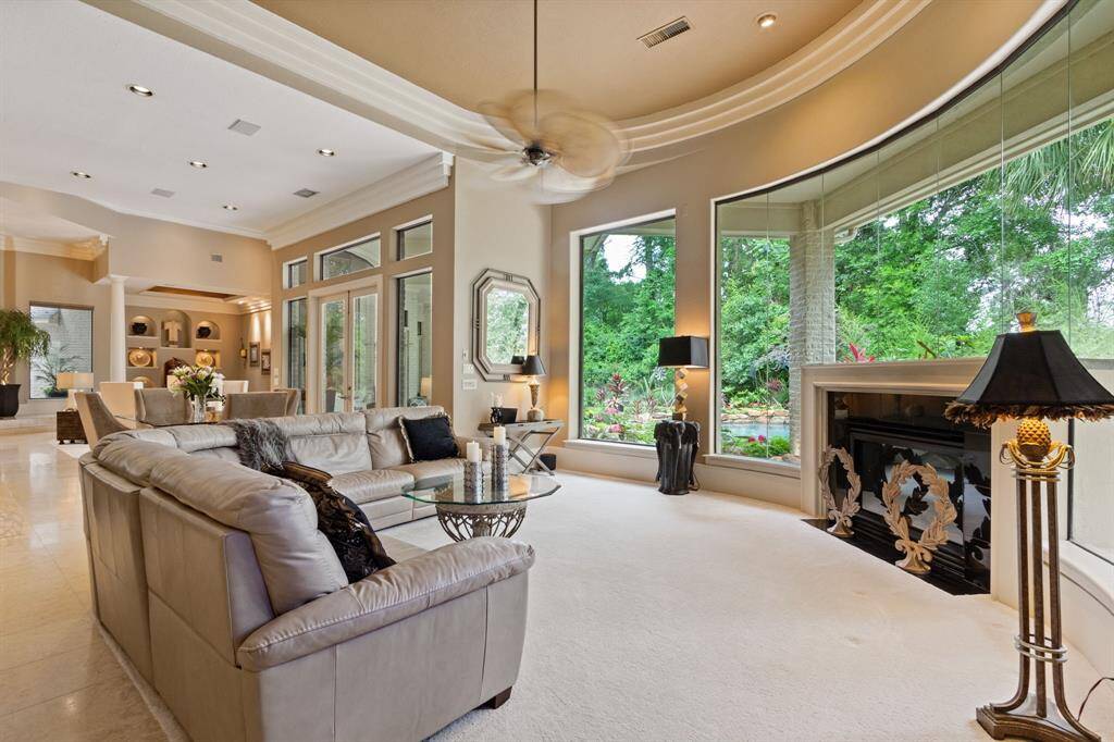 This spacious family room features a panoramic view through large windows. Elegant recessed lighting, and a cozy fireplace are featured.  The room creates a welcoming and relaxing atmosphere.