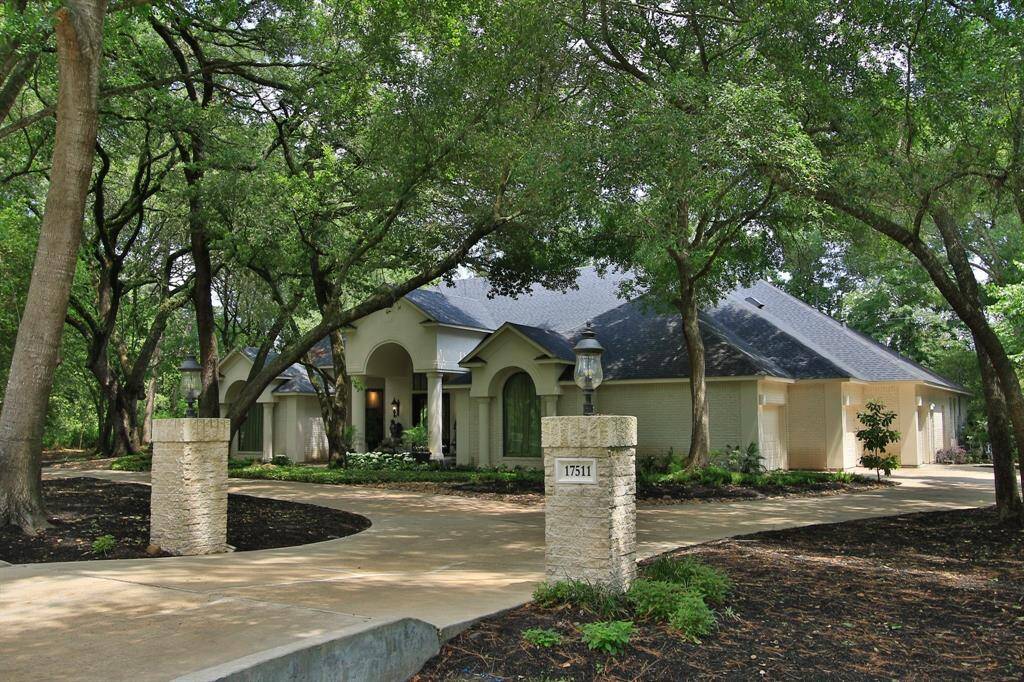 This elegant home is nestled among mature trees, offers stone stone columns with darling light fixtures. The property features a winding driveway as well as a convenient circular driveway leading to a well-maintained,  with a welcoming arched entrance. Lush landscaping enhances its curb appeal, making it a tranquil retreat.