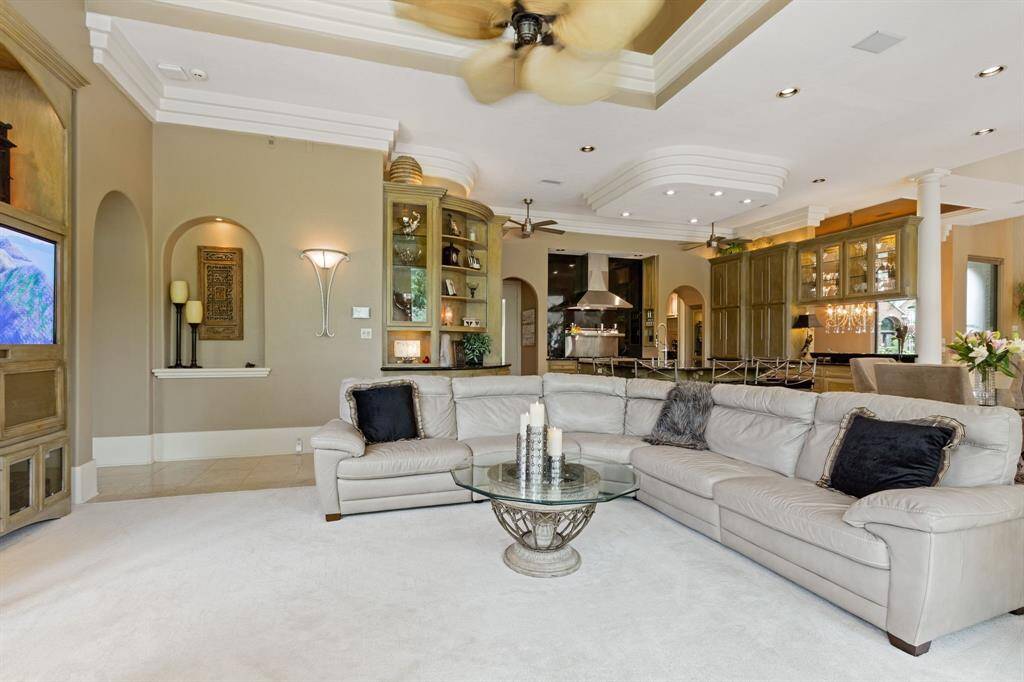 The open layout seamlessly connects to a modern kitchen with a central island, creating a perfect space for entertaining. High ceilings, recessed lighting, and decorative moldings add to the luxurious feel.