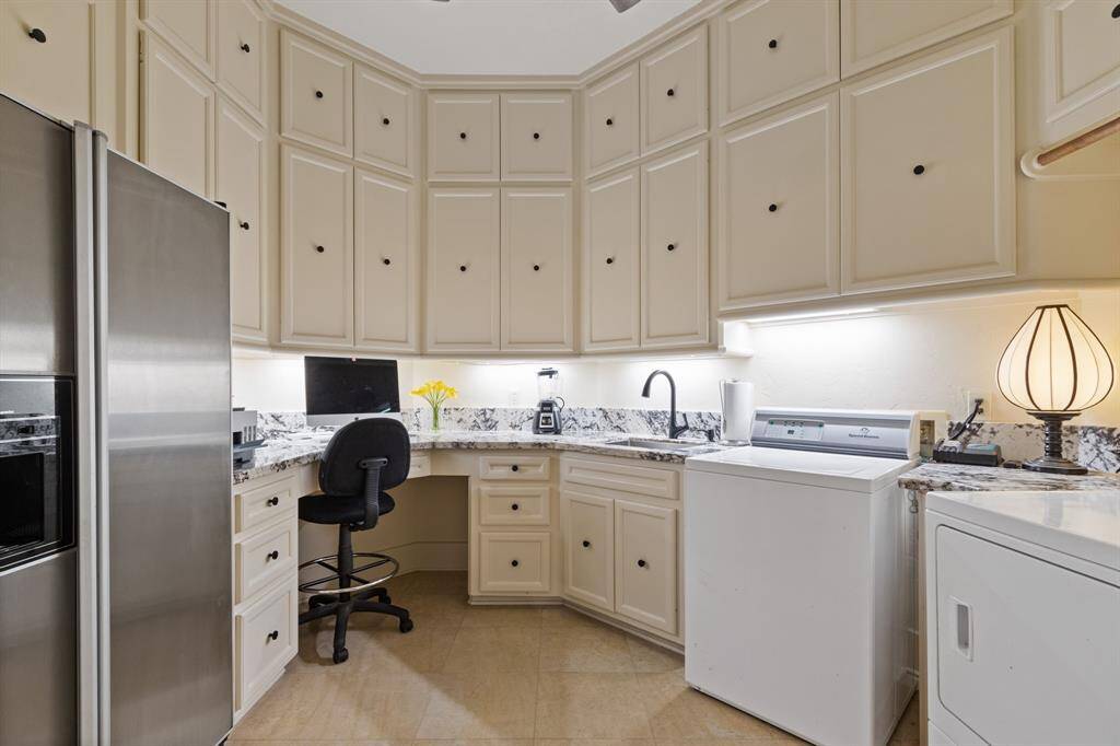 This main utility room boasts abundant cabinet storage, elegant granite counters, utility sink, and a convenient built-in desk. Wow!