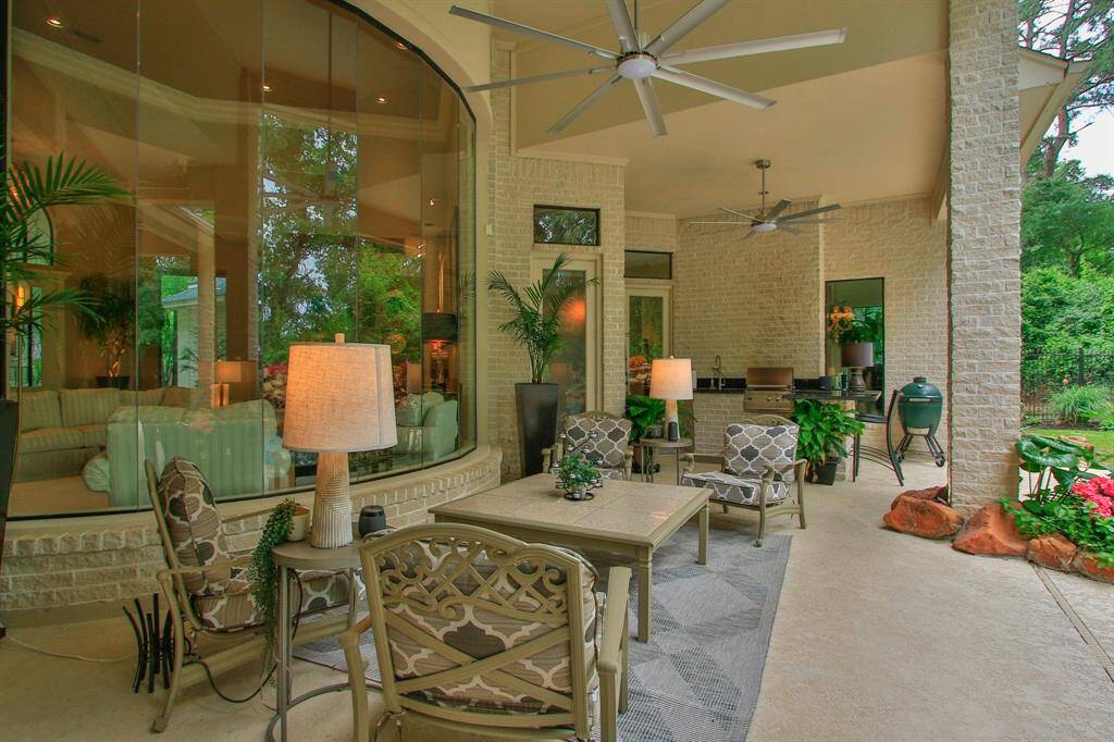 Outdoor living at it's best! This photo showcases a spacious, covered patio with plenty of room for your outdoor furniture, ceiling fans, and lush greenery. The area features a built-in grill, providing a perfect space for entertaining and relaxing with a seamless indoor-outdoor flow.