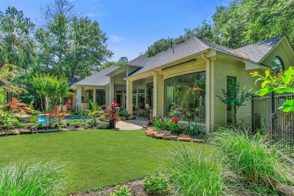 This photo showcases a charming home with a spacious, well-maintained backyard featuring lush landscaping and large windows. The exterior is bright and inviting, surrounded by mature trees, offering privacy and a serene atmosphere.