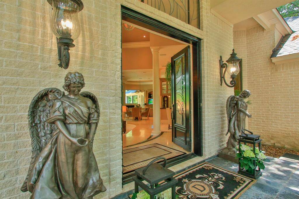 Elegant entrance with ornate lighting, leading through the double doors to a spacious, warmly lit interior with high ceilings and a welcoming atmosphere.
