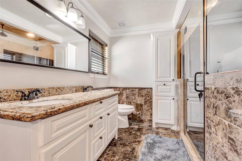The bathroom boasts dual vanities with granite countertops, a large walk-in shower.
