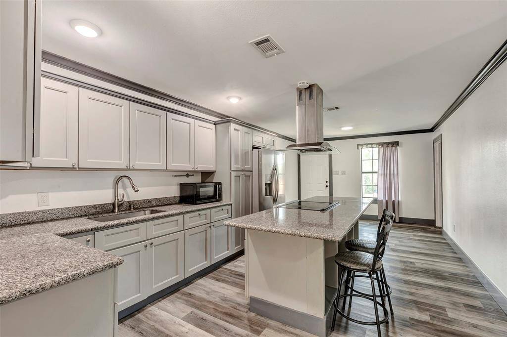 Beautiful kitchen featuring sleek granite countertops, custom cabinetry, and a spacious center island with bar seating.