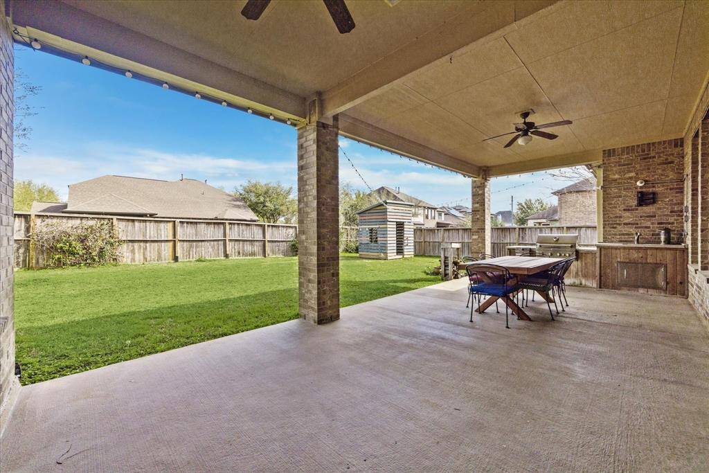 Enjoy endless hours of fun in the fenced-in backyard. Covered outdoor living features a summer kitchen, wired speakers, and two ceiling fans - the perfect place to relax or entertain.