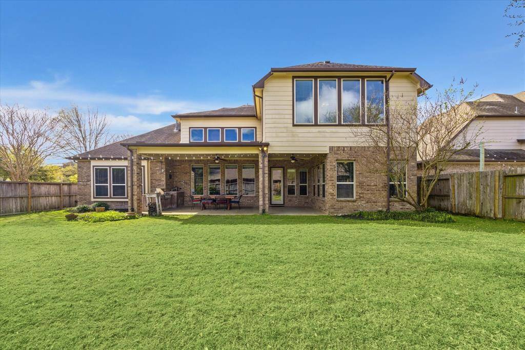 View of the back exterior showing the covered outdoor living and dining with summer kitchen.