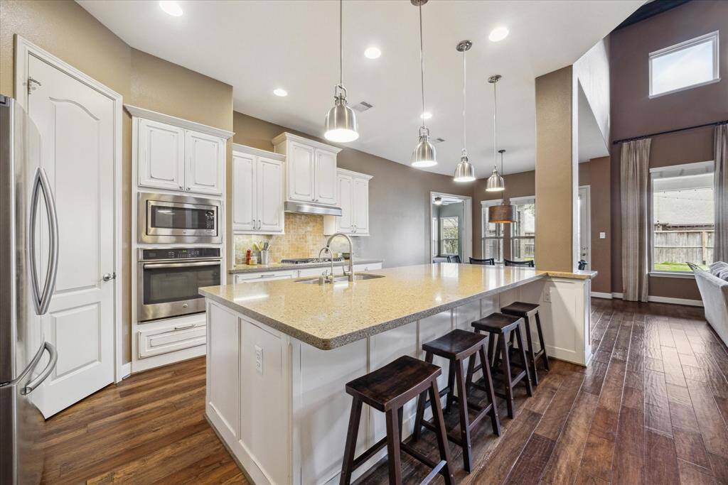 Gorgeous island kitchen features stainless steel appliances, gas cook top, tons of bar seating, and pantry.