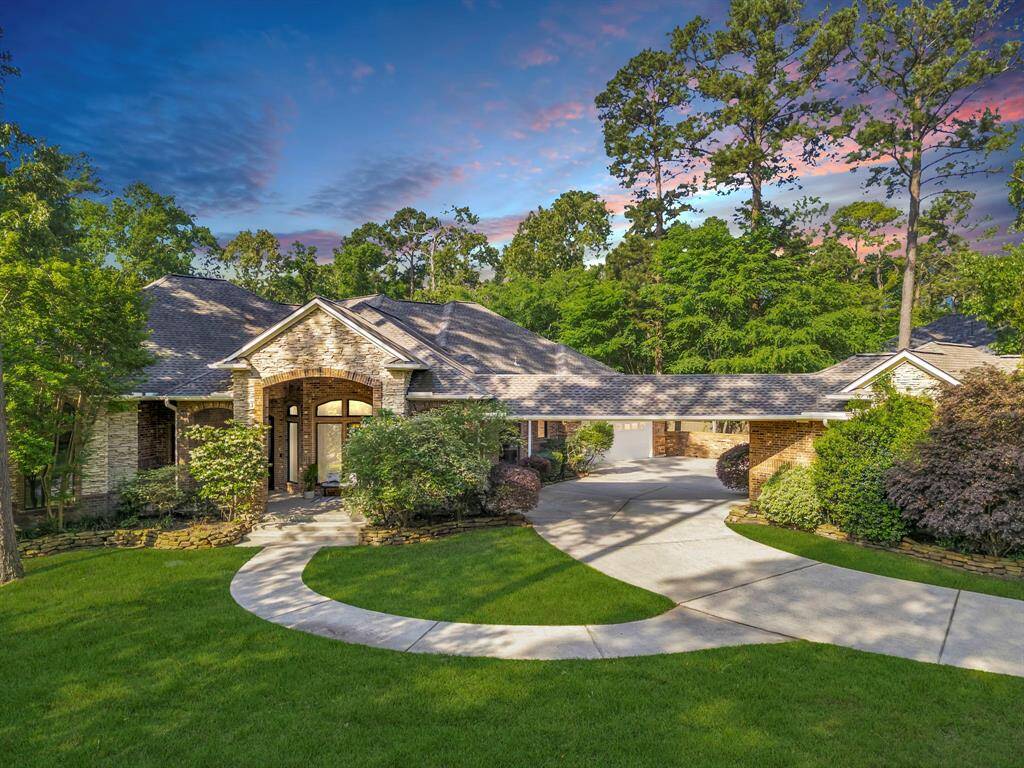Welcome to 18676 W. Cool Breeze—a gracious stone-and-brick estate framed by mature pines, manicured gardens, and an inviting arched porch entry that sets the tone for the luxury-style living found inside.