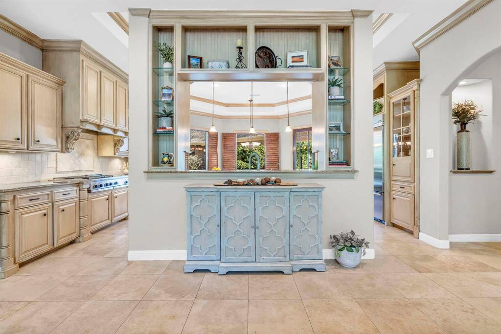 Decorative pass-through with custom display shelving and glass inserts offers a stylish sight-line from the kitchen to the living room while keeping the cook connected to guests.
