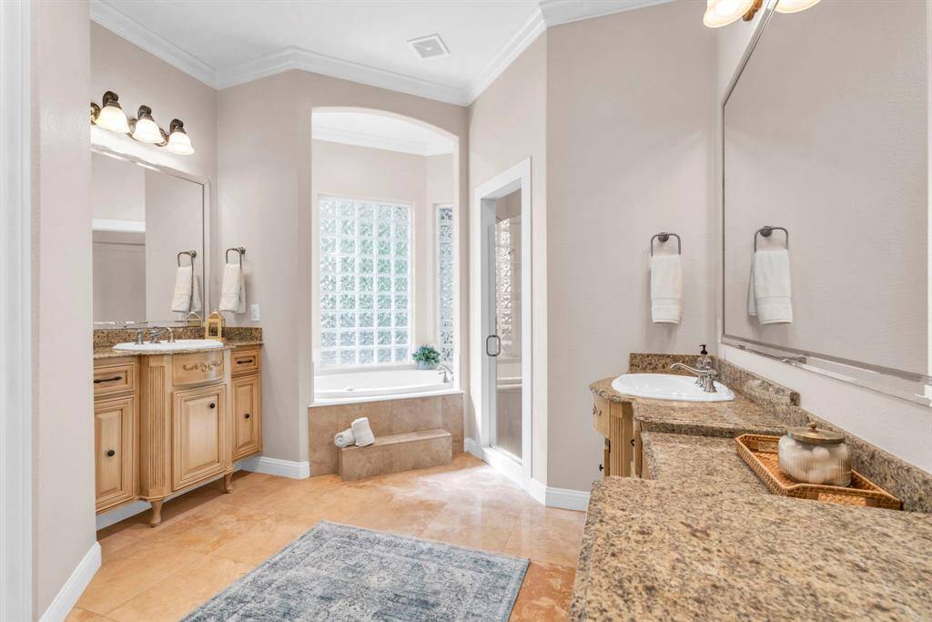 Alternate view of the luxurious primary bath highlighting the soaking tub set beneath a picture window —perfect for unwinding at day’s end.
