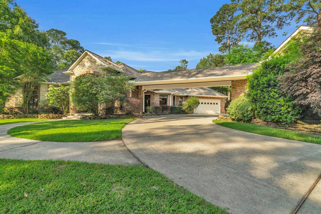 A large driveway leads to a porte-cochère and casita with 3rd detached garage, framed by mature trees, layered stone accents, and manicured landscaping for an impressive curb appeal and ample parking for guests.