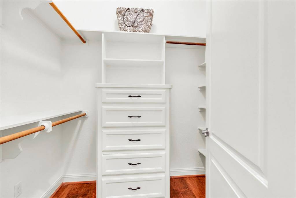 A spacious second primary closet featuring custom built-ins, ample shelving, and multiple hanging rods to effortlessly organize your wardrobe.