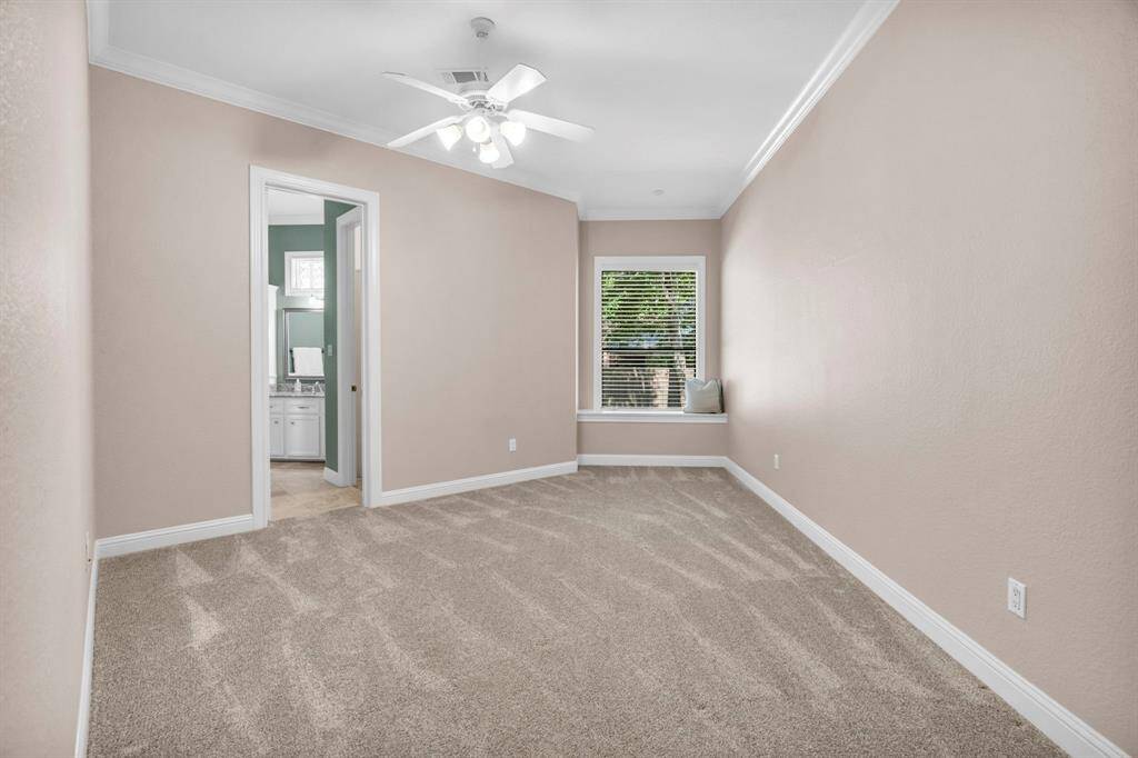 Bright, neutral secondary bedroom with crown molding, and a charming window seat—plus entrance to the Hollywood bath where you will find a large walk-in closet with built ins.