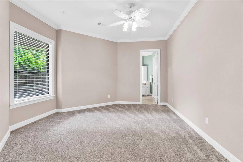 Another spacious, light-filled secondary bedroom that overlooks the backyard and pool, highlighted by crown molding, a large walk-in closet with built-ins, and private access to the Hollywood bath.