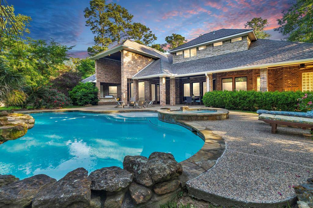 Resort-style backyard showcases a free-form pool, elevated spa, and stacked-stone waterfall glowing beneath the evening sky—perfect for alfresco dinners, late-night swims, and unforgettable gatherings.