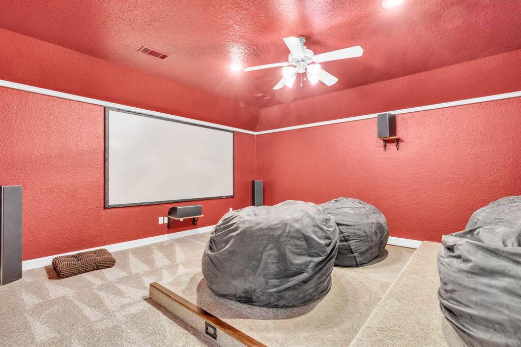 Across the catwalk you will find a dedicated media room with tiered platform seating, wall-to-wall screen, surround-sound wiring, and plush carpet—your ultimate movie-night retreat.