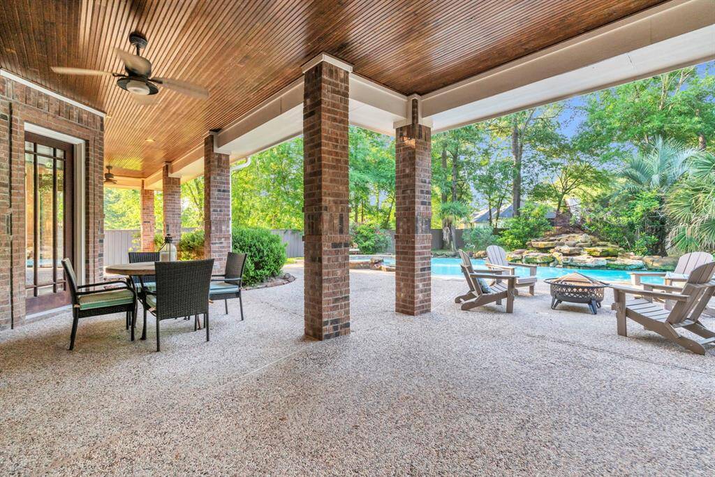 Expansive covered patio with rich tongue-and-groove ceiling, dual ceiling fans, and multiple seating zones delivers true indoor-outdoor living.