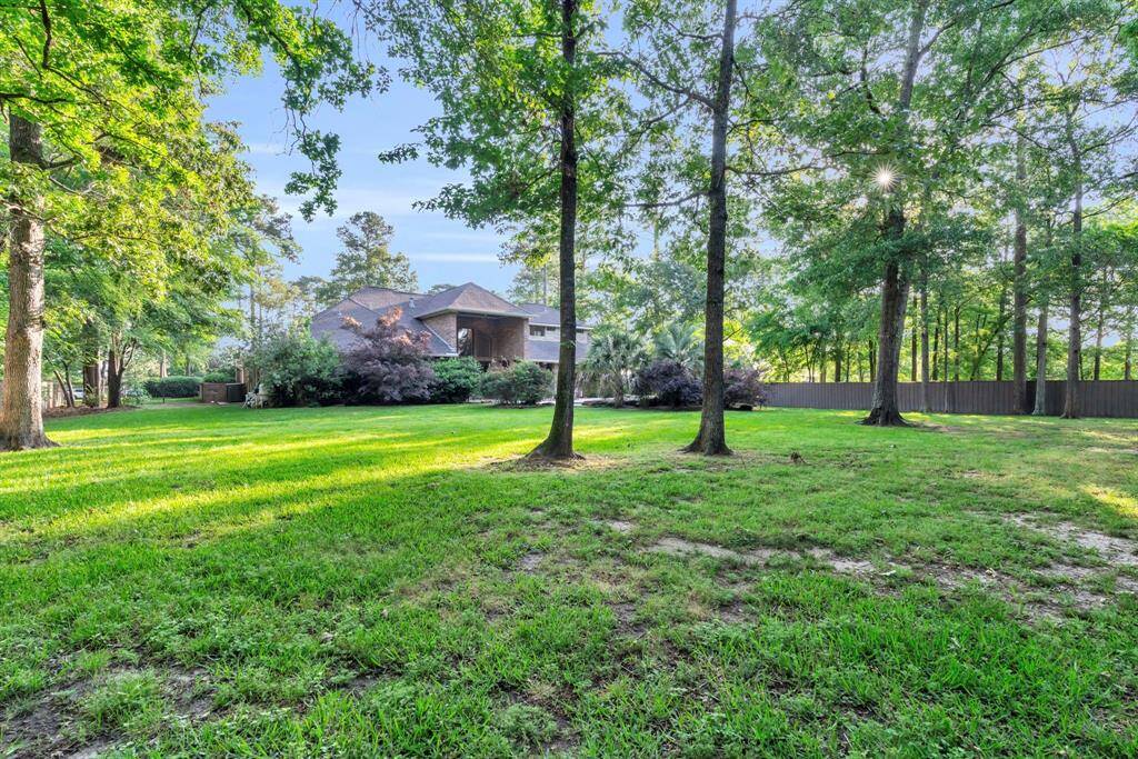 Park-like rear grounds with lush lawn and mature shade trees provide a tranquil buffer of privacy—and plenty of room to play or even a garden.