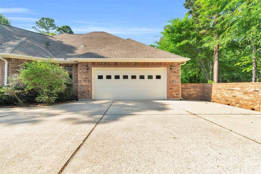 Oversized attached two-car garage finished with drywall and trim, featuring a convenient rear door to the backyard. A broad concrete apron adds generous space for extra parking, workshop projects, or organized storage.