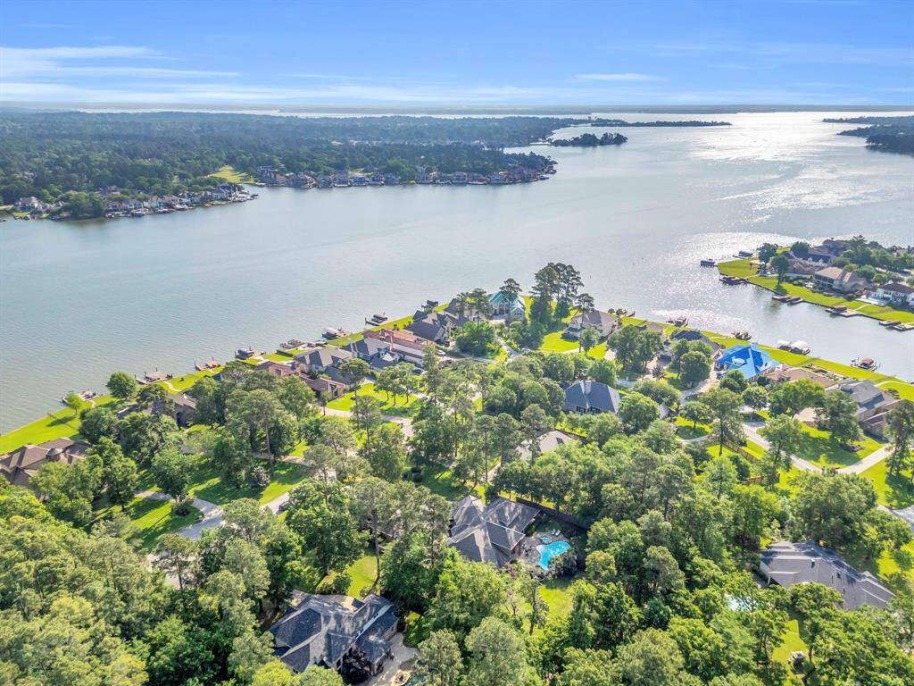 Bird’s-eye perspective reveals the home nestled on nearly an acre of wooded serenity, just seconds from the shoreline and neighborhood boat docks.