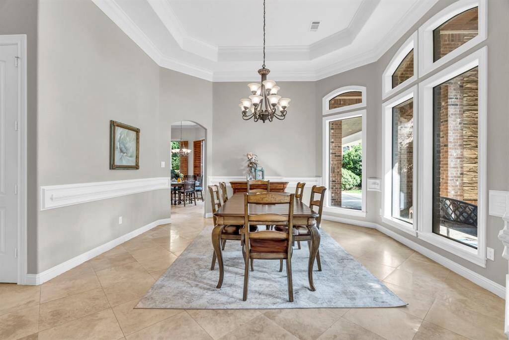 Alternate angle of the formal dining room highlights the expansive bay of windows, classic chair rail molding, and seamless flow through an arched hallway to the breakfast area and kitchen.