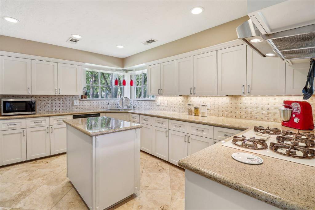 In the beautifully updated kitchen you'll find granite counters, custom travertine backsplash, island work surface, gas cooktop, and a cheerful kitchen window over the sink complete with pendant lighting and deep window sills perfect for growing kitchen herbs.