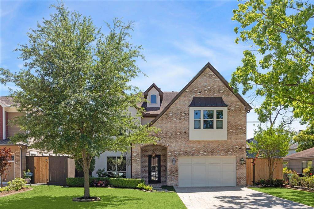 Stunning curb appeal with a blend of timeless brick and stucco exterior, this beautifully designed home sits on a well-manicured lot with mature trees and lush landscaping. A wide driveway leads to a two-car garage, while a charming covered entry welcomes guests through an arched brick surround. Thoughtful greenery, stone-lined flower beds, and a neatly edged lawn enhance the inviting facade, offering a glimpse of the care and quality found throughout the property.