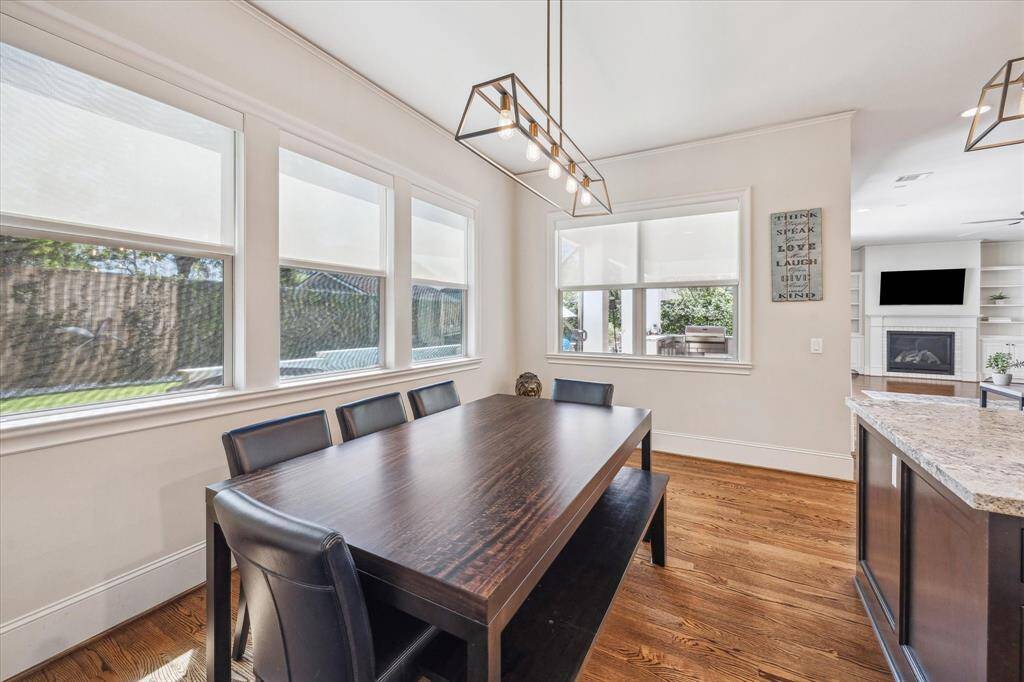 Flooded with natural light, this bright breakfast nook is framed by a series of large windows that offer serene views of the backyard. A modern light fixture adds a contemporary touch, while warm hardwood flooring and neutral tones create a seamless flow into the adjacent kitchen and living areas. This airy corner is ideal for enjoying quiet mornings or connecting during everyday moments.