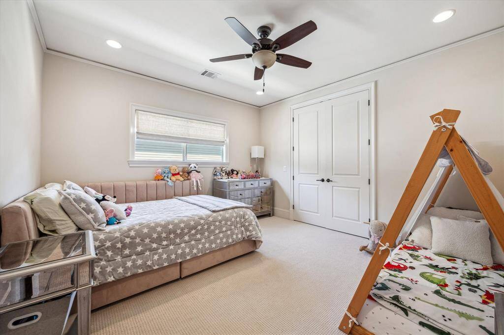 Light and airy secondary bedroom with neutral tones, plush carpeting, and recessed lighting throughout. A large window invites in natural light, while the layout provides ample space and comfort for guests or family members. Clean trim work, a large closet and a ceiling fan complete the polished look.