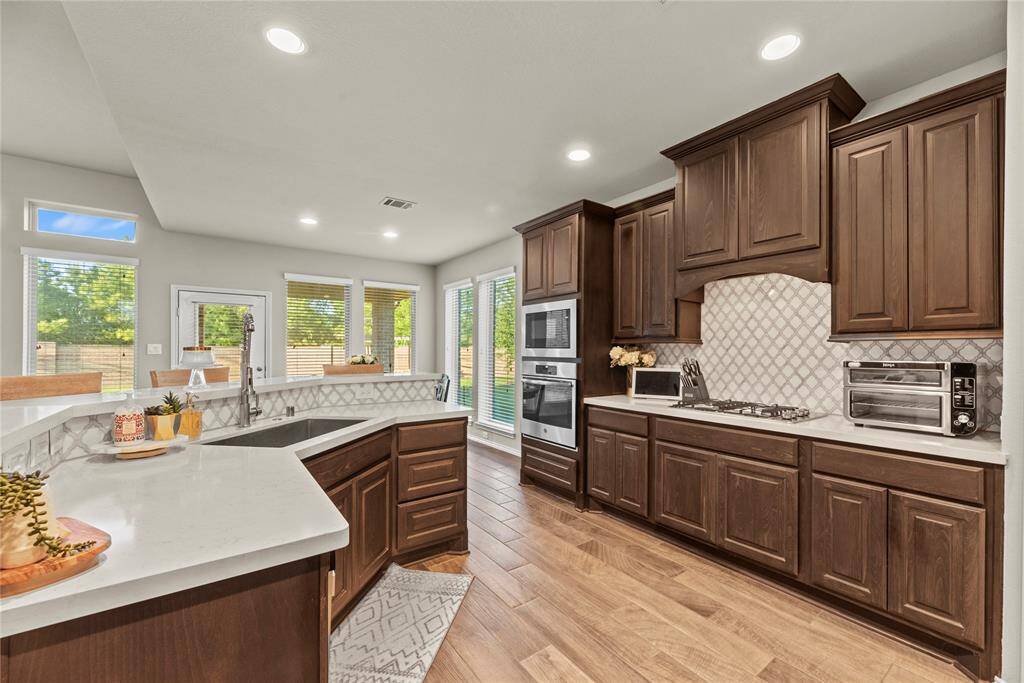 Gorgeous kitchen features Quartz countertops, stainless steel appliances, gas cooktop, refrigerator and marble backsplash.