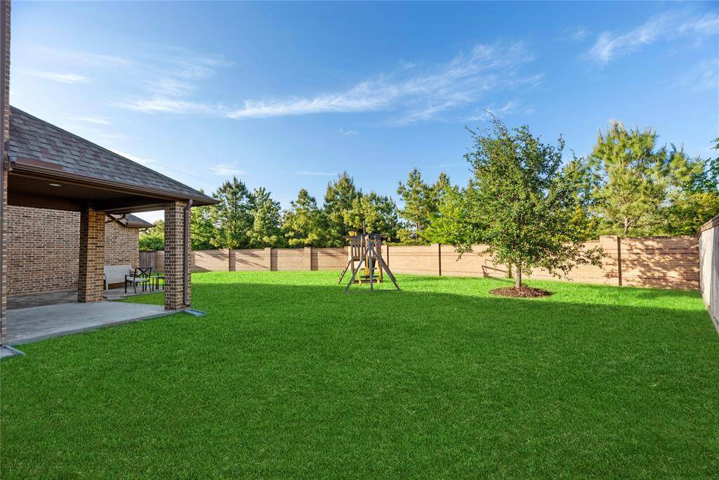 Huge backyard with a covered patio and brick wall.