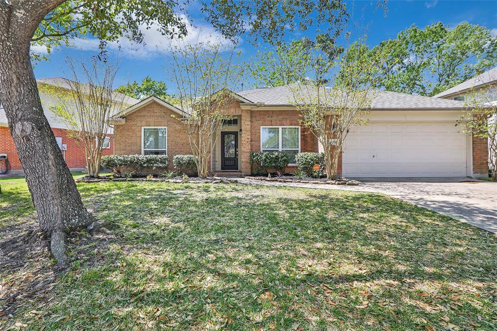 Charming brick home with a welcoming front yard featuring mature trees and well-maintained landscaping. It includes a two-car garage and a cozy front entrance, perfect for family living.