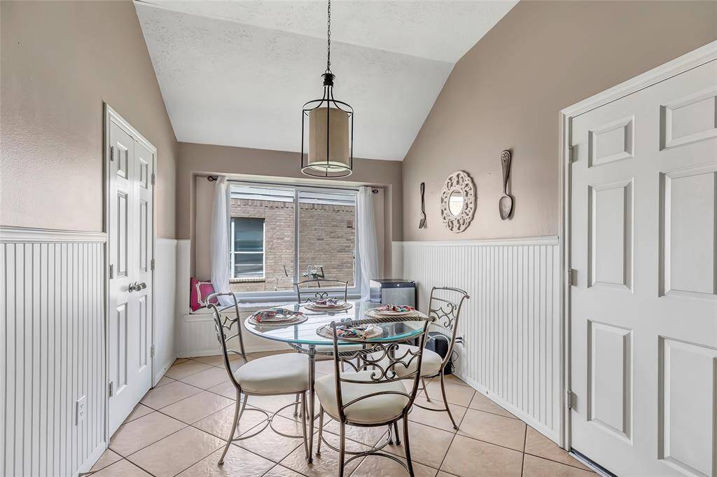 Bright breakfast nook with high ceiling & a large window inviting natural light, while wainscoting adds charm. Perfect for cozy meals.