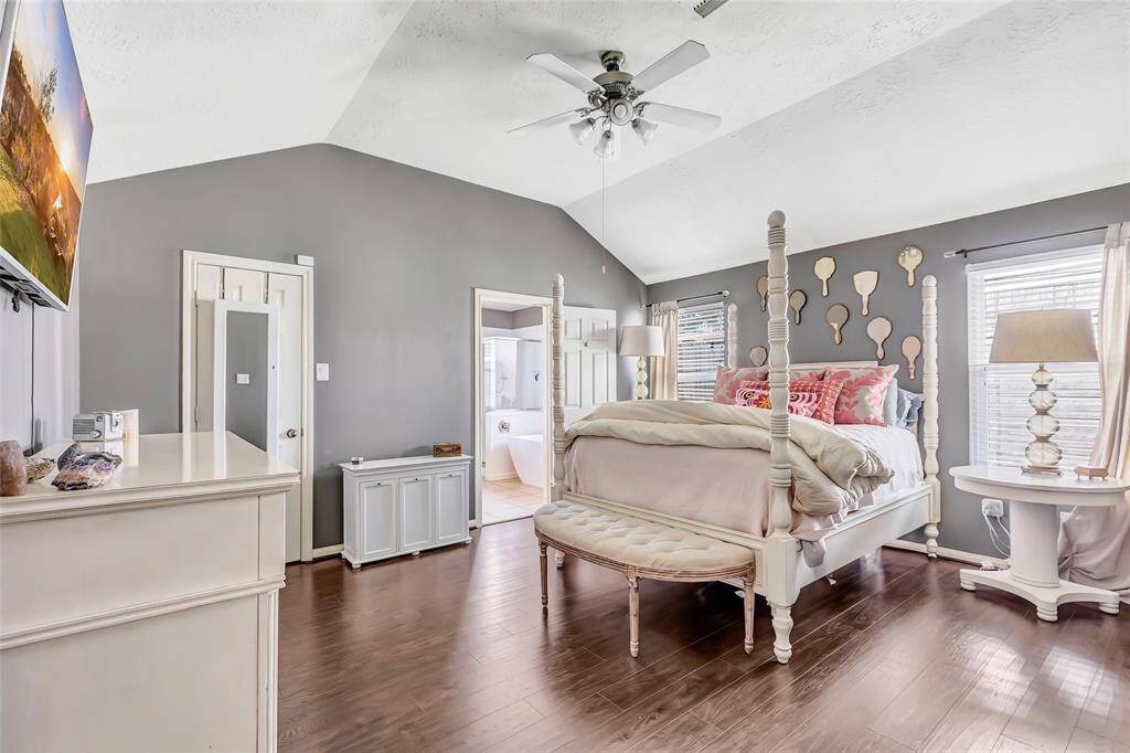 Primary bedroom features a vaulted ceiling, hardwood floors, and abundant natural light.