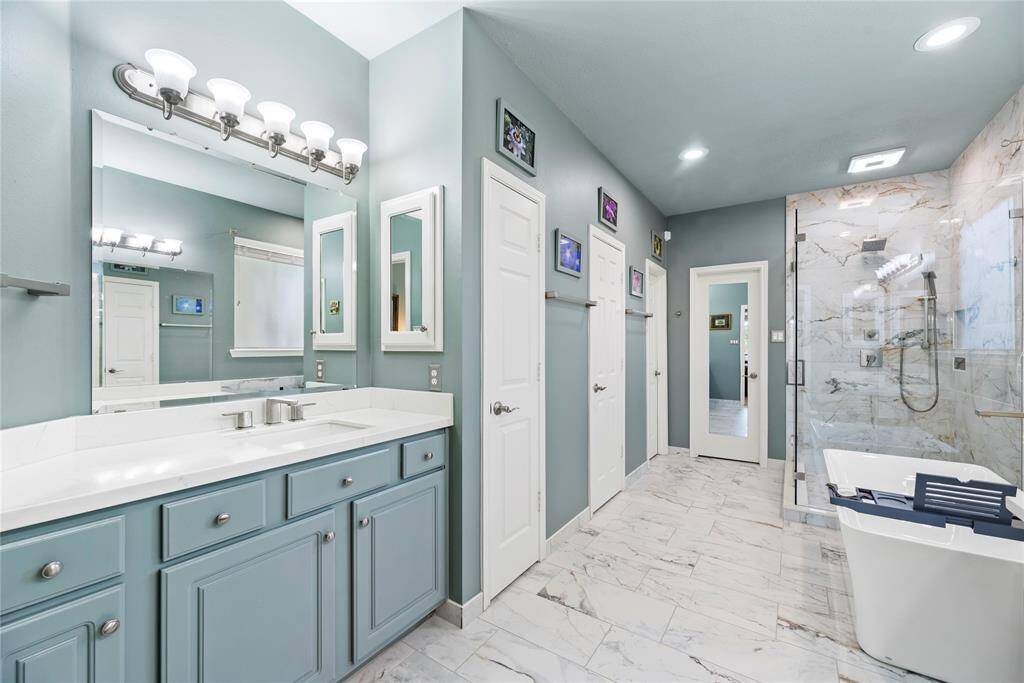 Elegant primary bathroom featuring a sleek countertop with sink, a separate soaking tub, and a glass-enclosed shower for a spa-like experience.