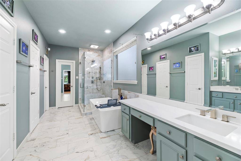 Alternate view of the primary bathroom showcasing the expansive countertop with ample cabinets and drawers for storage. This spacious bath also features two walk-in closets for ultimate convenience.