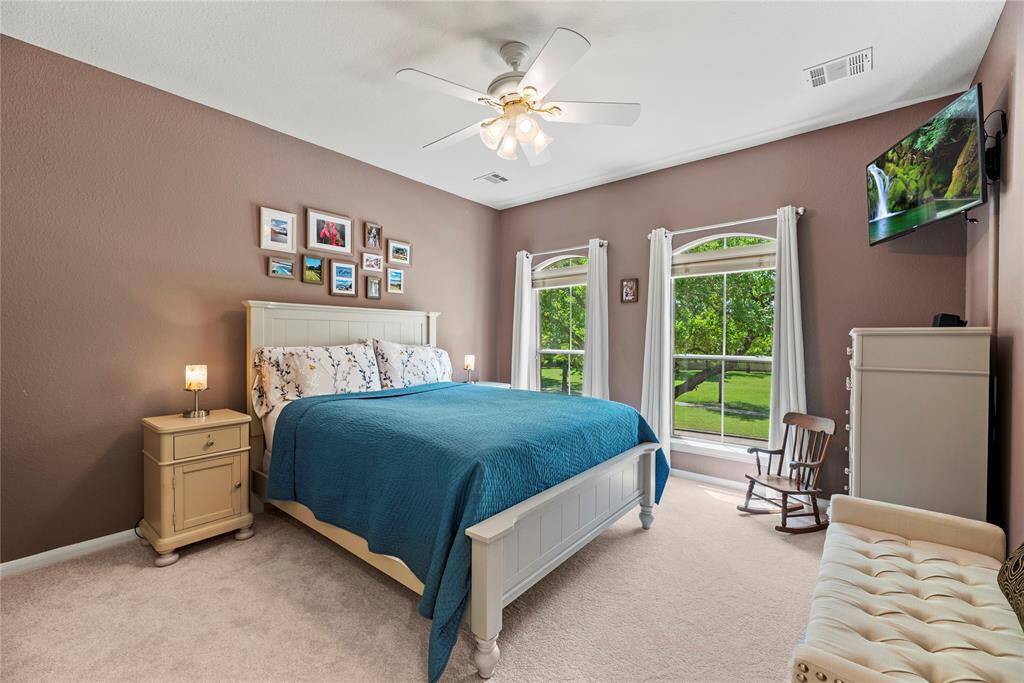 The second bedroom, measuring 12.6 x 14, features carpet flooring, a ceiling fan, and large windows offering a pleasant view of the front of the home.