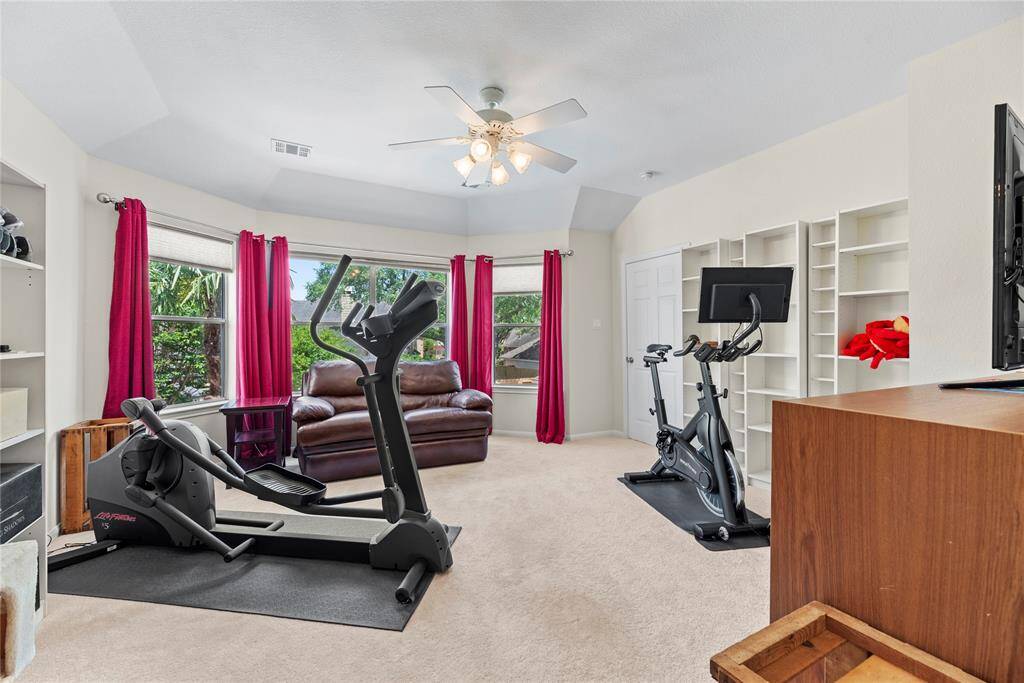 Spacious fourth bedroom measuring 14.3 x 15.5, featuring carpet flooring, a ceiling fan, and large windows with beautiful views of the backyard.