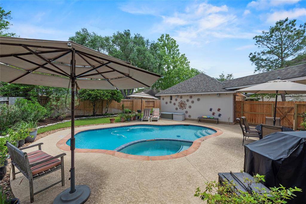 Alternate view of the backyard highlights the inviting pool with a spa. This angle also showcases the beautifully maintained landscaping along the side, adding charm and privacy to the outdoor space.
